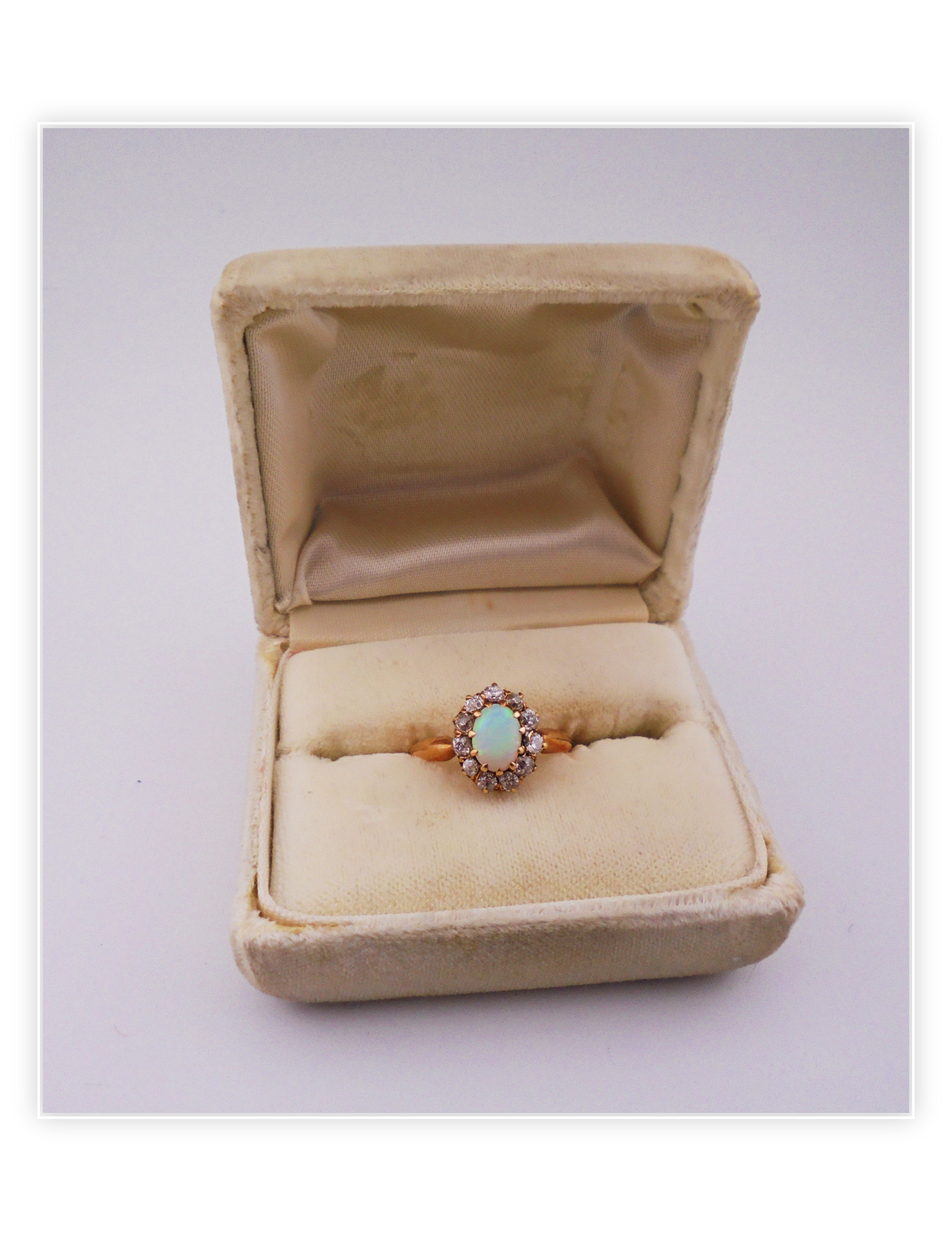 A gold ring with opal center stone and diamond halo