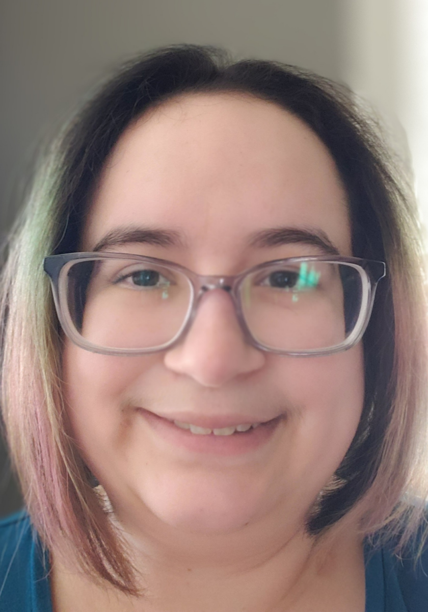 Veronica Gomez headshot. A white woman with faded blue and pink hair and glasses.