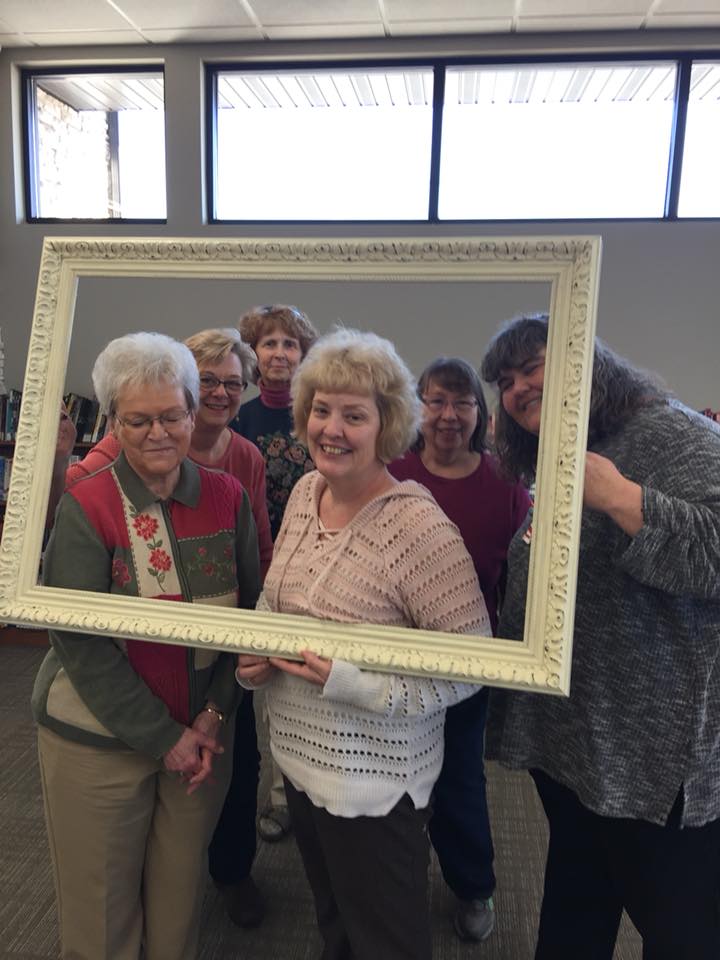 Litchfield librarians holding a large, empty photo frame